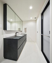 ダークトーンでまとめた洗面室。洗濯機は収納内に収め、すっきりとした空間に